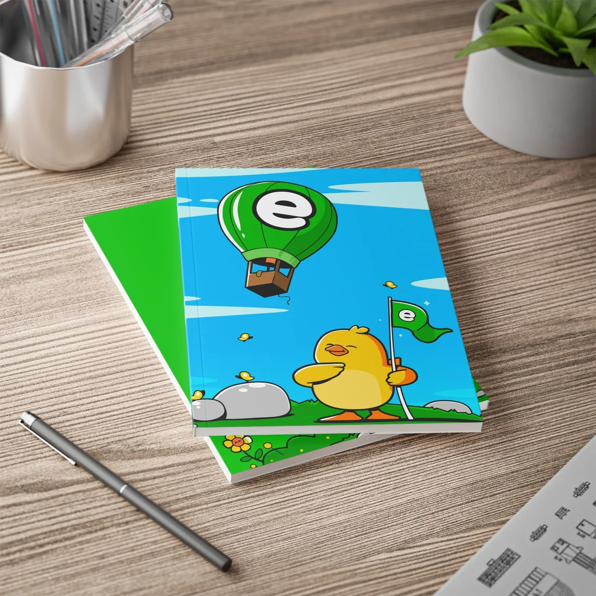 Blue A5 notebook with a duck and a hot air balloon on a wooden desk